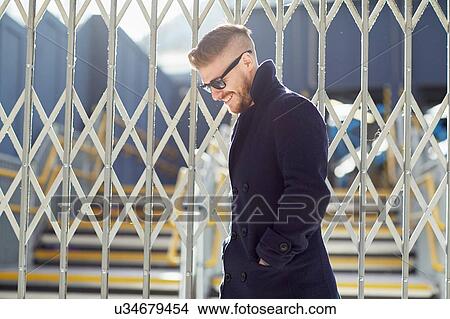 Young man standing by fence at train station View Large Photo Image Picture - Young man standing by fence at train station. Fotosearch
