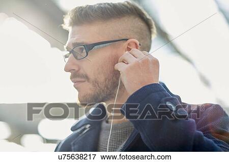 Young man wearing earphones, outdoors View Large Photo Image Stock Photo - Young man wearing earphones, outdoors. Fotosearch