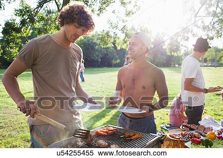 Young men barbecuing at sunset park party View Large Photo Image Stock Photography - Young men barbecuing at sunset park party. Fotosearch