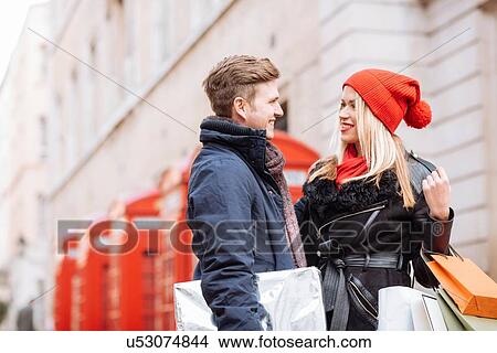 Picture - Young shopping couple and red phone boxes, London, UK. Fotosearch