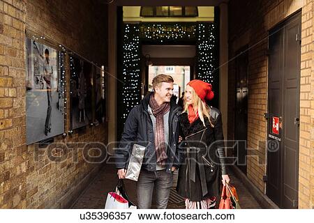 Stock Photo - Young shopping couple strolling in alley, Covent Garden, London, UK. Fotosearch