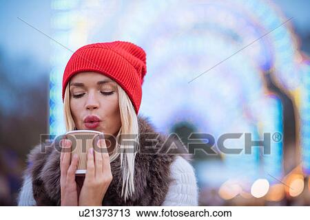 Young woman blowing on mulled wine at Xmas festival, Hyde Park, London, UK View Large Photo Image Stock Image - Young woman blowing on mulled wine at Xmas festival, Hyde Park, London, UK. Fotosearch