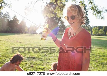 Young woman drinking wine at sunset park party View Large Photo Image Stock Photo - Young woman drinking wine at sunset park party. Fotosearch
