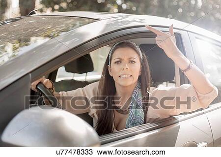 Young woman, driving, making hand gesture from open window View Large Photo Image Stock Image - Young woman, driving, making hand gesture from open window. Fotosearch