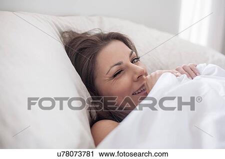 Young woman hiding under bed covers View Large Photo Image Stock Image - Young woman hiding under bed covers. Fotosearch