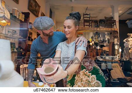 Young woman holding pink vase in vintage shop View Large Photo Image Stock Photo - Young woman holding pink vase in vintage shop. Fotosearch