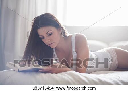 Young woman in lying n bed, reading book View Large Photo Image Picture - Young woman in lying n bed, reading book. Fotosearch
