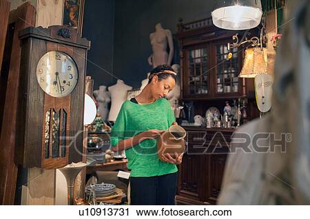 Young woman looking at jug price ticket in vintage shop View Large Photo Image Stock Image - Young woman looking at jug price ticket in vintage shop. Fotosearch