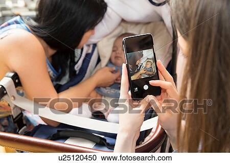 Young woman photographing mother and baby daughter on smartphone View Large Photo Image Stock Image - Young woman photographing mother and baby daughter on smartphone. Fotosearch