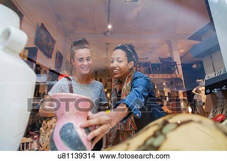 Young woman shopping for pink vase in vintage shop View Large Photo Image Picture - Young woman shopping for pink vase in vintage shop. Fotosearch