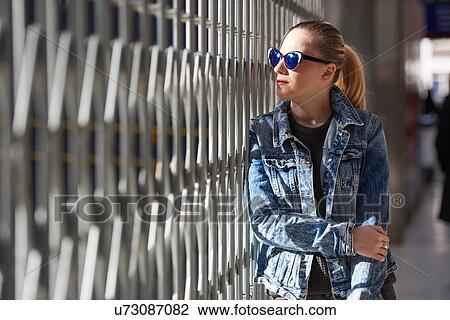 Young woman standing beside metal fence, pensive expression View Large Photo Image Stock Image - Young woman standing beside metal fence, pensive expression. Fotosearch