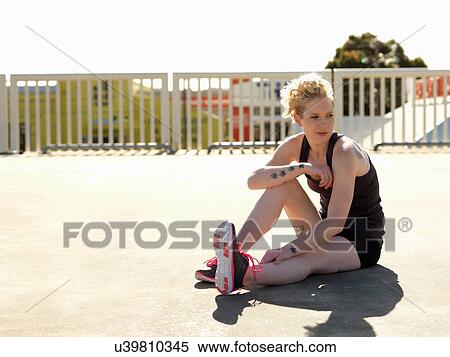 Stock Photography - Young woman taking a break from training in urban parking lot. Fotosearch