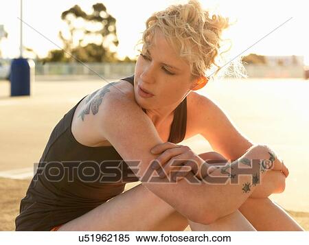 Stock Photography - Young woman taking a training break in parking lot. Fotosearch