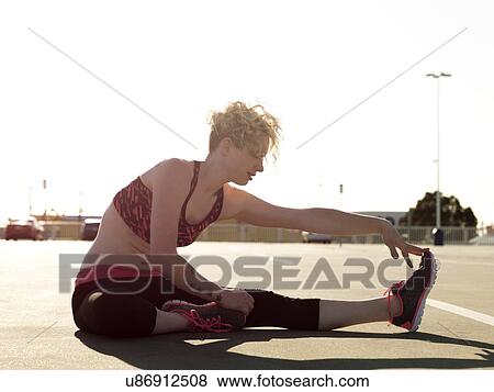 Young woman touching her toes whilst training in parking lot View Large Photo Image Stock Photo - Young woman touching her toes whilst training in parking lot. Fotosearch