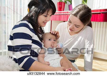 Young woman with mother and baby daughter on floor View Large Photo Image Picture - Young woman with mother and baby daughter on floor. Fotosearch