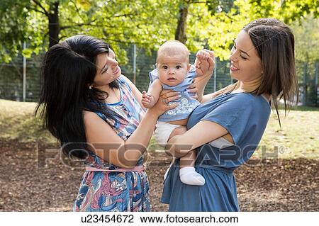 Stock Image - Young woman with mother and baby daughter in park. Fotosearch