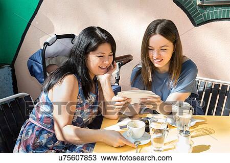 Young woman with mother and baby daughter looking at photographs at sidewalk cafe View Large Photo Image Stock Image - Young woman with mother and baby daughter looking at photographs at sidewalk cafe. Fotosearch