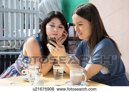 Young woman with mother and baby daughter reading smartphone text in cafe View Large Photo Image Stock Photo - Young woman with mother and baby daughter reading smartphone text in cafe. Fotosearch