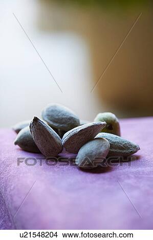 Picture - Almonds in shell on purple colour table cloth. Fotosearch