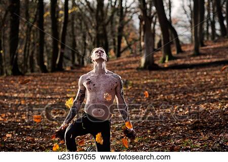 Bare chested tattooed man kneeling on autumn leaf covered forest floor looking up View Large Photo Image Stock Photography - Bare chested tattooed man kneeling on autumn leaf covered forest floor looking up. Fotosearch