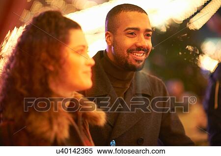 Stock Photography - Bearded mid adult man with young woman looking away smiling. Fotosearch