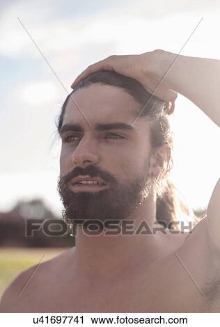 Stock Image - Bearded young man with ponytail. Fotosearch