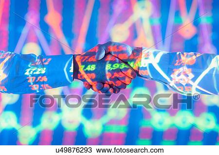 Stock Image - Businessmen shaking hands with projected graphical financial data, close up. Fotosearch