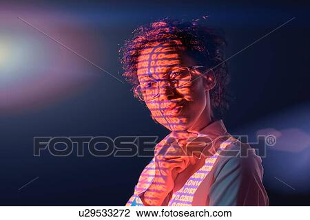 Stock Image - Businesswoman in thought with projected financial numbers on dark background. Fotosearch