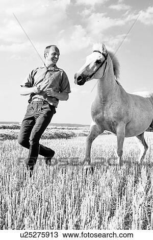 B&W image of male trainer running in front of white horse in field View Large Photo Image Stock Image - B&W image of male trainer running in front of white horse in field. Fotosearch