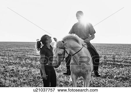 B&W image of woman chatting with man riding grey horse in field View Large Photo Image Stock Photo - B&W image of woman chatting with man riding grey horse in field. Fotosearch