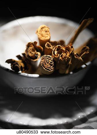 Stock Image - Cinnamon sticks in a white vintage bowl. Fotosearch