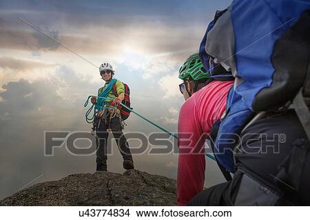 Picture - Climber on mountain top holding rope for partner, Mont Blanc, France. Fotosearch