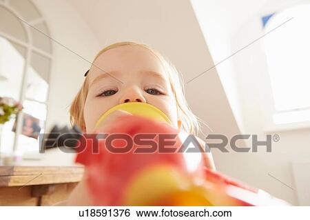 Stock Photograph - Close up of female toddler playing toy trumpet. Fotosearch