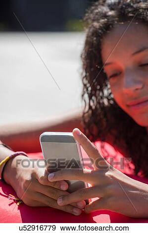 Stock Photo - Close up of girl on poolside reading smartphone texts. Fotosearch
