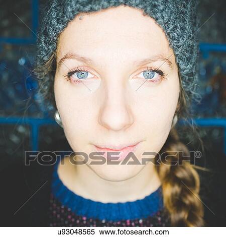 Stock Photography - Close up portrait of young woman with plaited hair wearing knit hat looking at camera smiling. Fotosearch