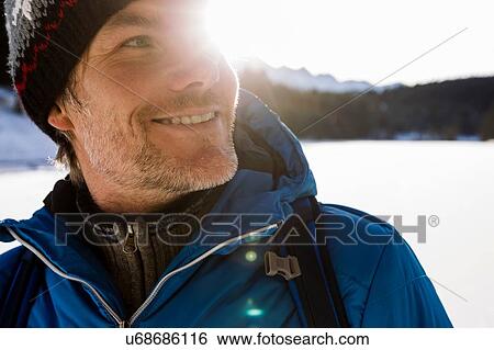 Stock Photograph - Close up sunlit portrait of mature man hiking in snow covered landscape, Berg, Bavaria, Germany. Fotosearch
