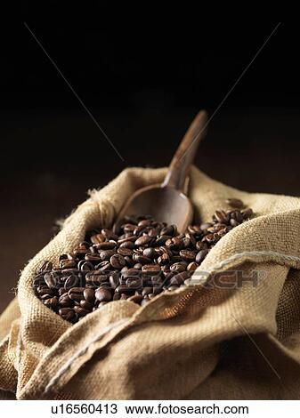 Stock Image - Coffee beans and wooden scoop in woven sack. Fotosearch