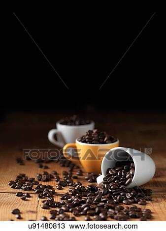 Coffee beans in espresso cups spilling onto wooden table View Large Photo Image Stock Image - Coffee beans in espresso cups spilling onto wooden table. Fotosearch