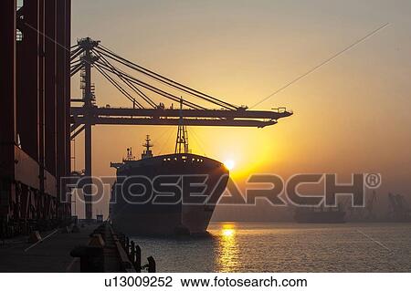 Stock Image - Container ship and cranes at port. Fotosearch