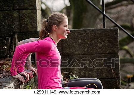 Stock Photo - Couple, hands behind back doing push ups on stone steps, looking away smiling. Fotosearch