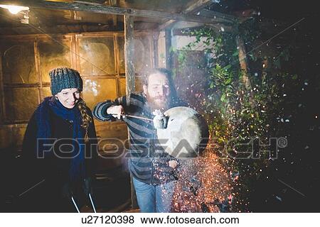 Couple holding hot clay pot in tongs, blowing, causing sparks View Large Photo Image Stock Photo - Couple holding hot clay pot in tongs, blowing, causing sparks. Fotosearch