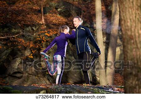 Couple in forest leaning against each other leg raised holding foot stretching View Large Photo Image Stock Photo - Couple in forest leaning against each other leg raised holding foot stretching. Fotosearch