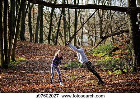 Couple in forest using resistance band on tree View Large Photo Image Stock Photo - Couple in forest using resistance band on tree. Fotosearch