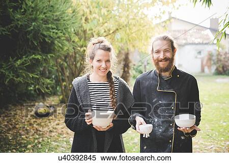 Stock Photography - Couple in garden holding clay pots looking at camera smiling. Fotosearch