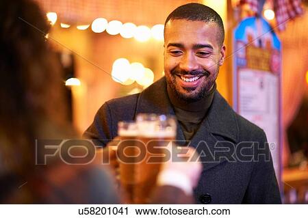Couple on night out, holding beer glasses making a toast smiling View Large Photo Image Stock Image - Couple on night out, holding beer glasses making a toast smiling. Fotosearch