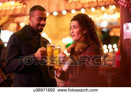 Couple on night out holding glass on beer making a toast View Large Photo Image Stock Image - Couple on night out holding glass on beer making a toast. Fotosearch