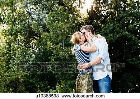 Stock Photo - Couple sharing passionate kiss in park. Fotosearch