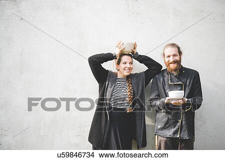 Couple standing in front of wall holding pots looking at camera smiling View Large Photo Image Picture - Couple standing in front of wall holding pots looking at camera smiling. Fotosearch