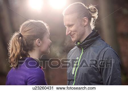 Stock Image - Couple wearing sports clothing face to face smiling. Fotosearch