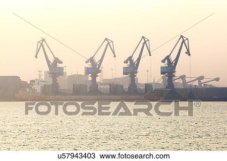 Cranes at port during sunrise View Large Photo Image Stock Image - Cranes at port during sunrise. Fotosearch